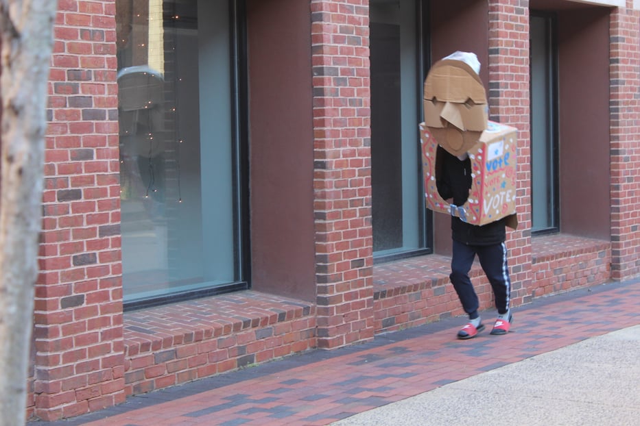 A student dressed as a ballot box marches down the street