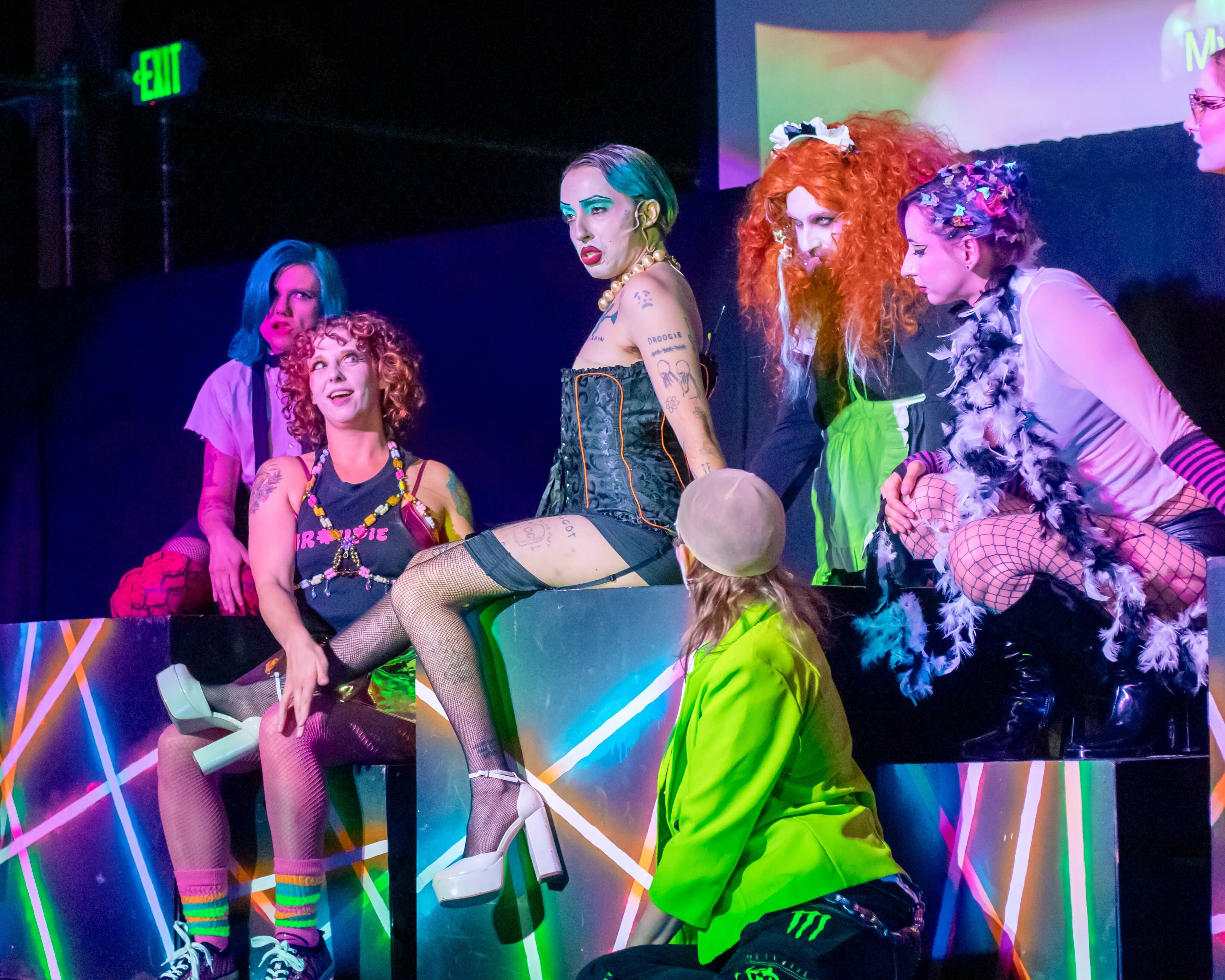 A group of performers in loud, risqué outfits pose on stag || Seven Phillips as Frank-N-Furter, Erin Carney as Columbia, Michael Domangue as Magenta, Miranda Rector, and Jamie-Lee Meintjes as Phantoms (Picture credit: Tony DeZinno)