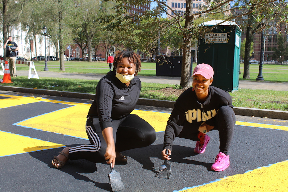 Stephanie Washington and Paige Steward touch up the mural