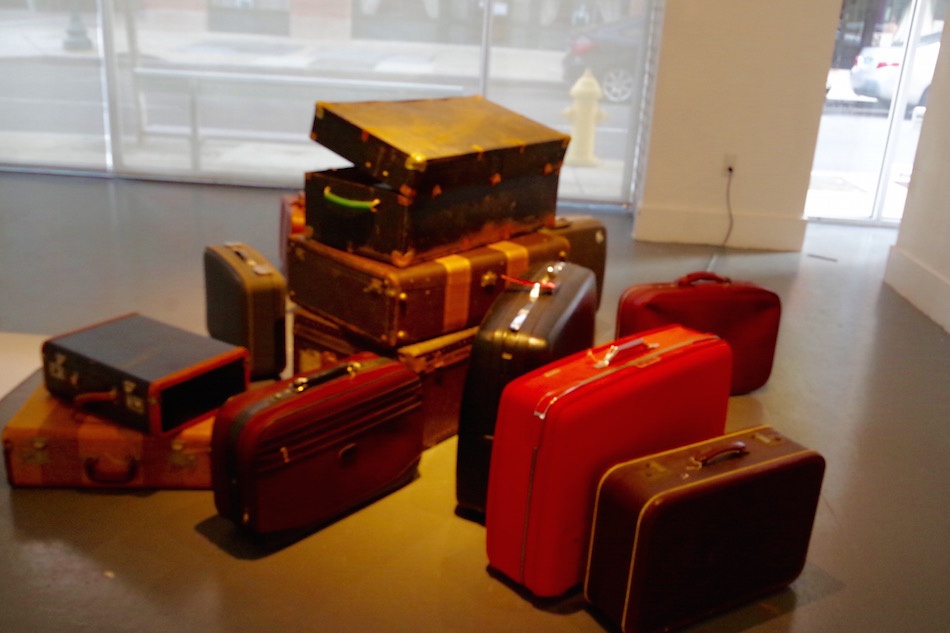 An introductory room with video and piles of baggage situate attendees to the exhibition.