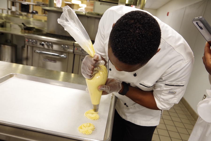 The demo continues with piped spritz cookies. Participants like Daniel Mugaburu learned the hard way that getting the dough onto the sheet isn't as easy as it may look.