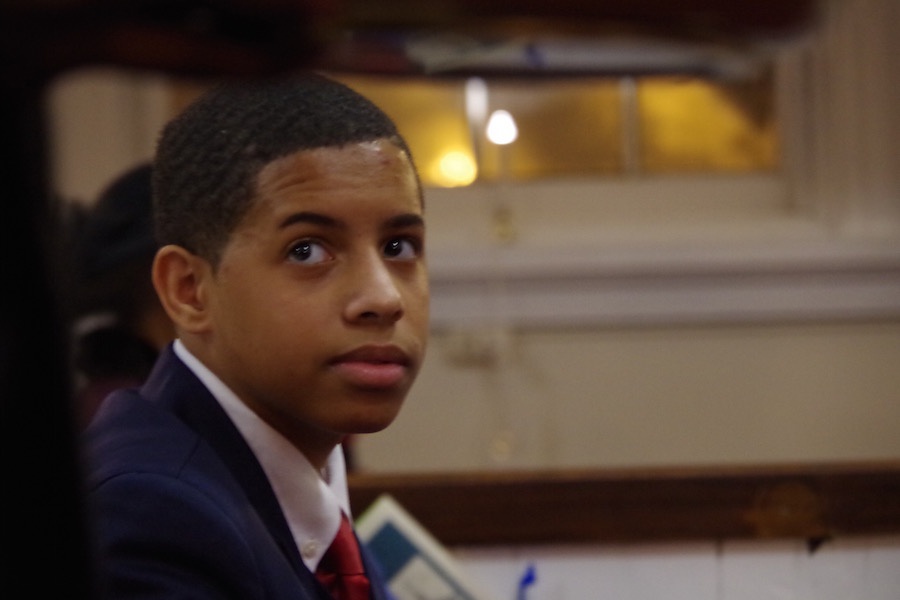  Ryan Klauder, a seventh grader at DOMUS academy, looks on as a plate for a freewill offering is passed around. Lucy Gellman Photo.&nbsp; 