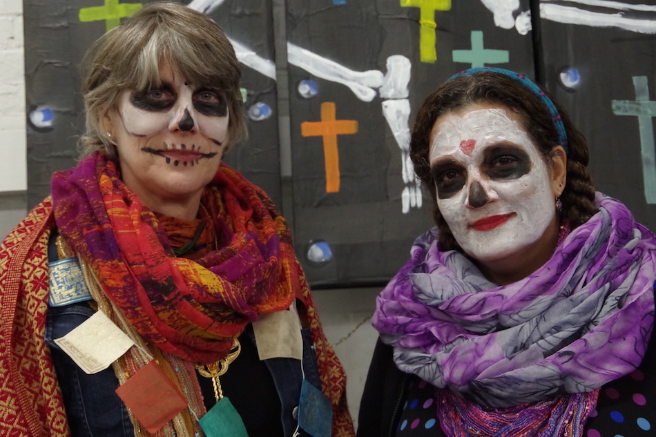 Friends Amy James and Ruthann Coyote pose against one side of the painted wall.